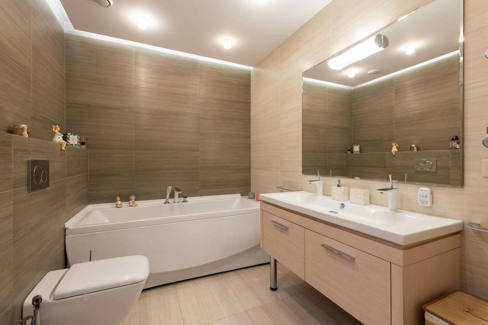 A contemporary bathroom featuring a bathtub, dual sinks, and ambient lighting.